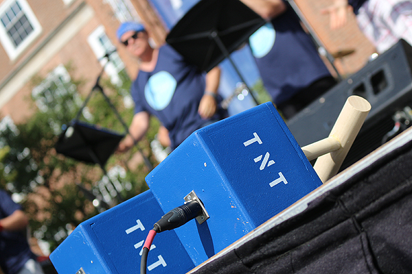 BRIAN BAKER/TOWN CRIER  TAKING CARE OF FUNDING: Prop TNT boxes, with plungers, sit in the foreground while UCC principal Jim Power performs "Taking Care of Business". Members of the school community pushed the plungers to unveil the $103.2 million dollars raised for the school through the Think Ahead Campaign. 