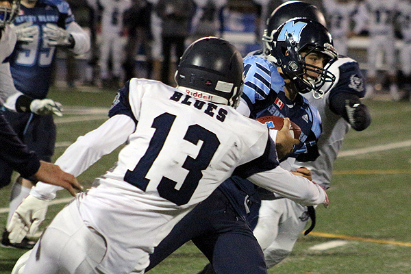 BRIAN BAKER/TOWN CRIER AVOIDING THE TACKLE: St. Mike's quarterback, Jonas Hatcher, squeezes out of UCC defender Patrick Stevenson's grasp during the two teams' Friday Night Lights match, Oct. 23. 